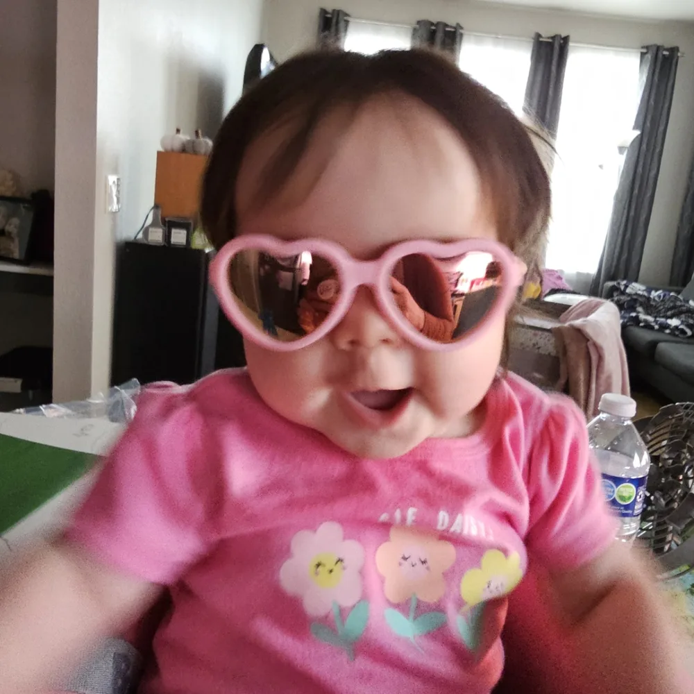 Baby wearing pink heart-shaped sunglasses